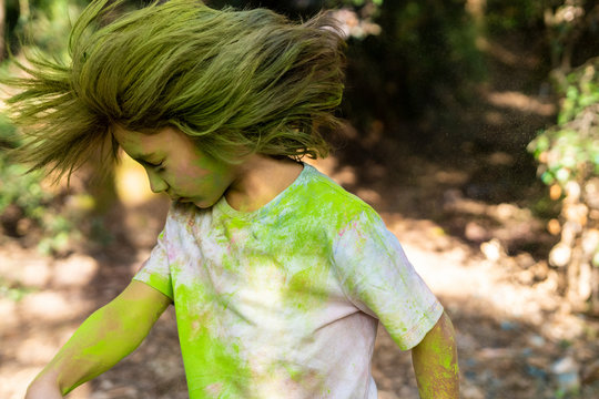 Boy shaking his head, full of colorful powder paint, celebrating Holi, Festival of Colors