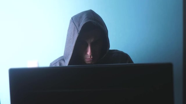 man hacker in the hood concept. unknown hacker criminal breaks into computer protection lifestyle on the Internet passwords. male hacker penetrates into hack network protection web phishing technology
