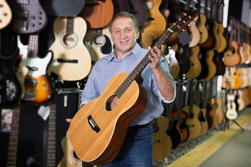 male is standing with modern guitar