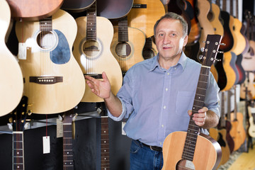male is standing with modern guitar