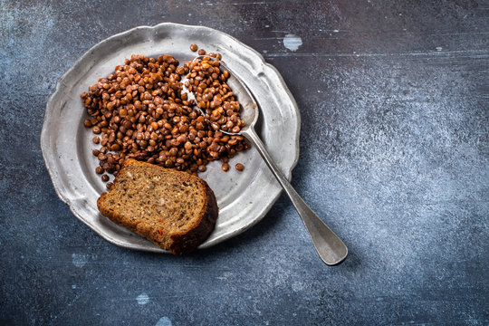 Lentils with bread on a metal plate with a spoon in a grunge setting. Poor and lacking nutrition
