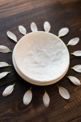 Obraz na płótnie Canvas Skin care. The concept of solar skin care. White mask for the body and face on a wooden table in the video of the sun. Petals in the shape of the sun.