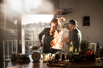 Friends flambeing food in a pan, producing a big flame