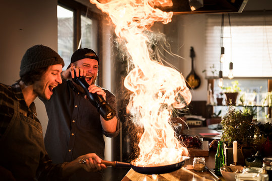 Friends flambeing food in a pan, producing a big flame