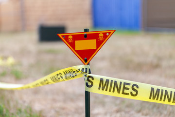 land mine warning sign stands on grass