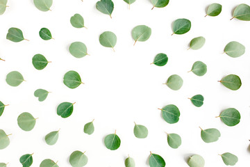 The workspace is decorated with green eucalyptus leaves, floral pattern on a white background. The apartment lay, top view.