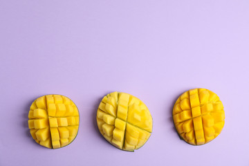 Cut tropical ripe mangoes and space for text on color background, top view
