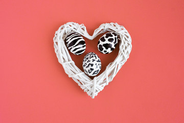Set of easter eggs painted like zebra, cow, snow leopard inside a white hearton coral background. Top view.