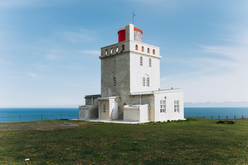 Fototapeta na wymiar White lighthouse on the shore of the ocean. Lighthouse in Iceland.