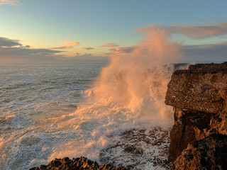 Wave crushes on a cliff at sunset making huge splash, West coast of Ireland, Burren region, Concept beautiful storm