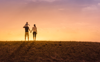 Obraz premium Happy family moment. Parents with their little child watching a beautiful sunset