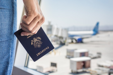 Hand holding USA passport at airport.  - obrazy, fototapety, plakaty