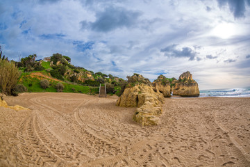 Beach, cliffs and green hills with stairs in the famous Alvor, Algarve, Portugal