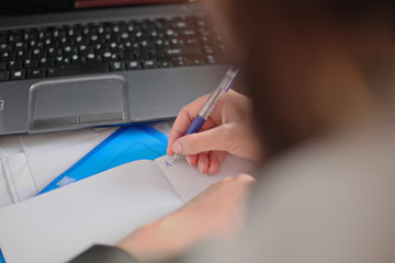 Workspace with laptop, girl's hands, notebook.Female working with laptop at home -Image