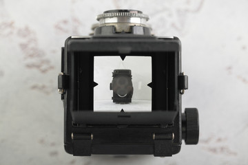 The old medium format film TLR camera on white cement background. Top view of the camera viewfinder. - obrazy, fototapety, plakaty