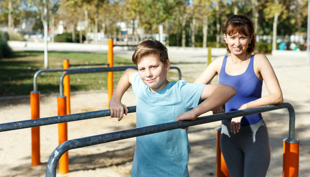 Family exercising on parallel bars outdoors