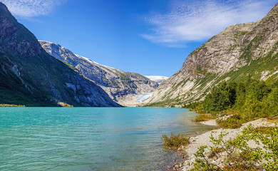 Norwegian landscape with milky blue glacier lake, glacier and green mountains. Norway