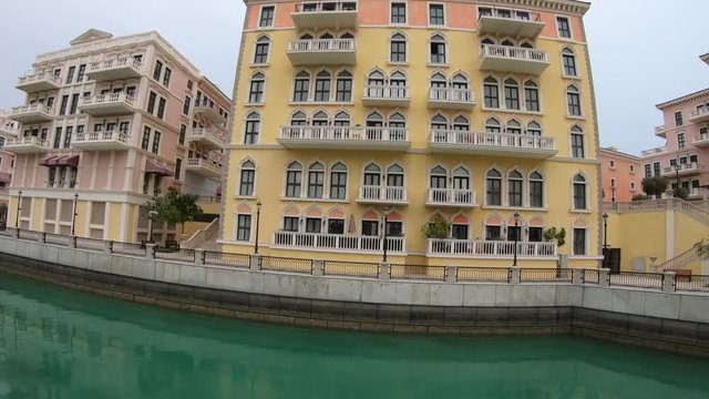 Little Venice with canals connected by bridges in venetian style. Colorful houses in picturesque Qanat Quartier icon of Doha, Qatar at sunset light. Venice at the Pearl, Persian Gulf, Middle East.