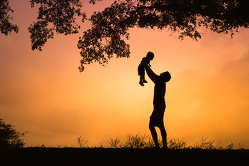 Happy father and son outdoors. Father holding up his little boy in the air.