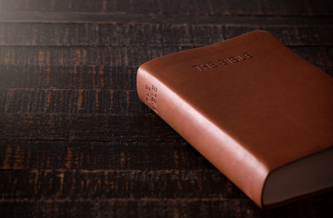 Bible on a Wooden Table in a Dark Environment