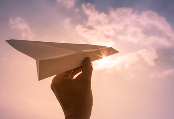 Hand throwing paper airplane. Flying high in the sky. Freedom, travel concept. 