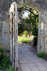 Antique wooden garden door in a garden wall, East Sussex, UK.