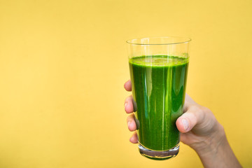hand holding a glass of green juice