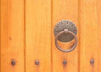 Ancient wooden gate with a door knocker ring close-up 