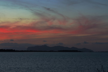 Tramonto con nuvole rosse e isola all'orizzonte