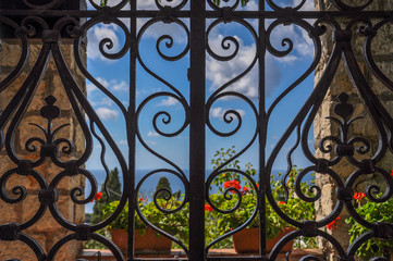 Fototapeta na wymiar Wrought iron gate with sea and flowers in the background