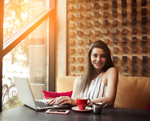 Young pretty caucasian woman in cafe in city centre with tablet laptop