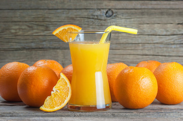 freshly squeezed orange juice in glass with orange fruits on wooden background, bitter seville fresh oranges citrus fruit concept