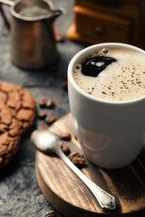 Black fried coffee beans in cafe with cookie and cake on dark textured background