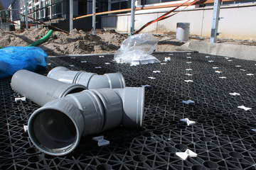 Large grey pcv pipes laying at an unfinished construction site