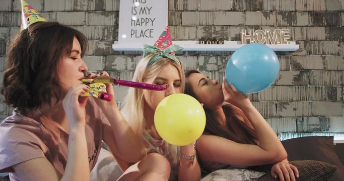 Awesome young ladies closeup have a pajamas party at home celebrating the the someone s birthday very happy and enjoyed the time spending together in front of the camera playing with colored balloons