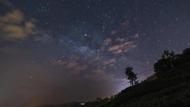 Beautiful nature time lapse, milky way stargazing with cloudy and hazy weather at Boh Tea plantation, Cameron Highlands, hill and a tree as foreground. Zoom out motion effect, 4k UHD.
