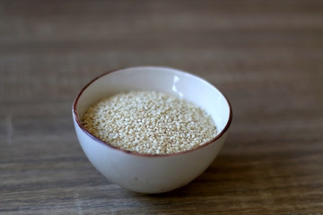 Small bowl of sesame on a wooden table. Selective focus.