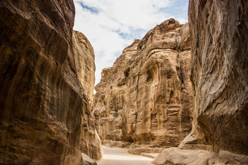 canyon wilderness sandstone steep rocky mountain narrow path way between steep mountain walls famous Middle East Jordan touristic site  outdoor environment place - Powered by Adobe