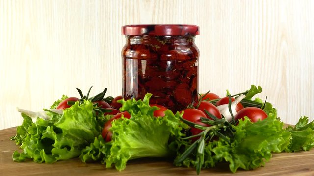 Tomatoes, dried tomatoes, garlic and lettuce leaves on a board. Slow motion.