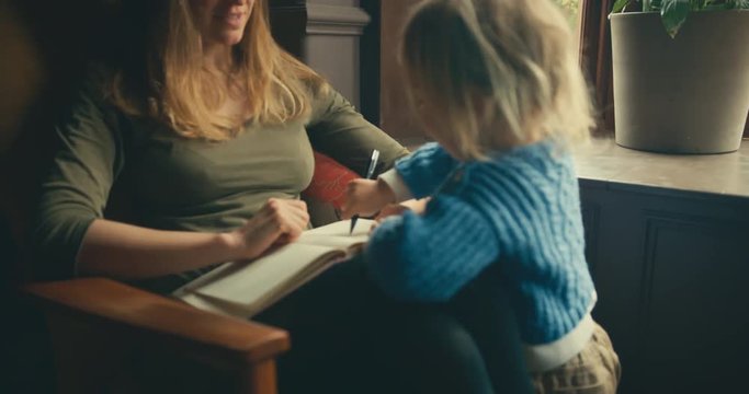 Toddler writing in mother's notebook