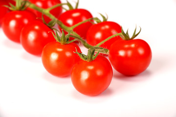 Ripe fresh Juicy organic cherry tomatoes closeup on branch isolated on a white background.