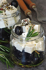 Feta with olives, olive oil and rosemary in a jar. Keto diet. Keto snack. Feta and olives marinated in spices and olive oil. Italian snack.