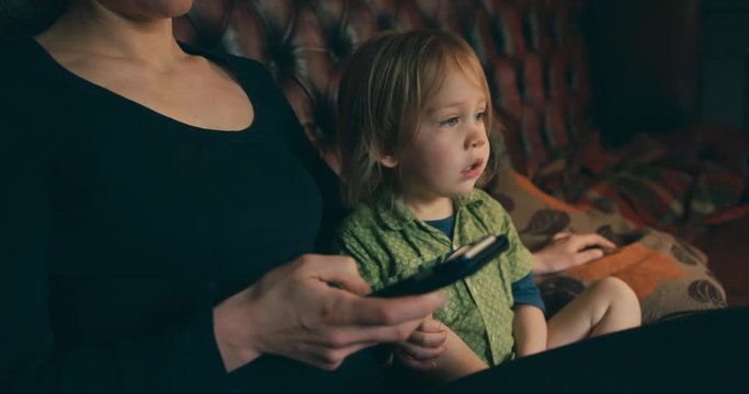 Mother using smartphone and ignoring toddler watching television