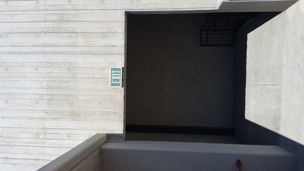 Green exit sign on concrete or stone wall with dark doorway