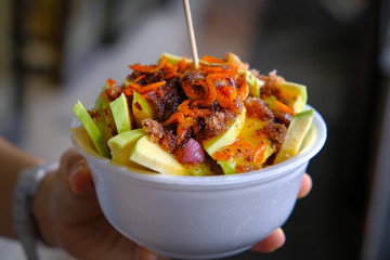 Fruit salad, Background of healthy fresh fruits, Mango fruit salad, in a bowl on a person's hand. (Thai food)