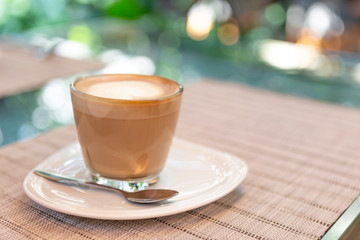 Hot coffee late in clear coffee cup over blurred garden background, outdoor morning light