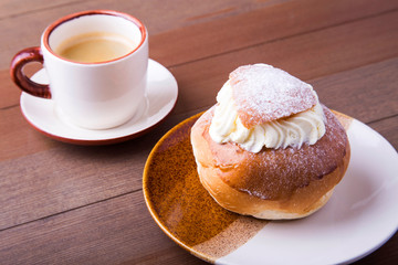 Swedish Semla, traditional Shrove bun, consists of light wheat bread with almond paste and whipped cream filling. cup with coffee.