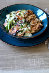 Fried chicken with sesame and zucchini and carrot salad with yoghurt sauce. Selective focus.