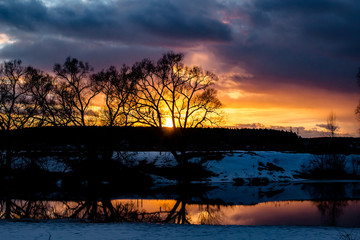 Scenic sunset over the trees above the river, colorful sky