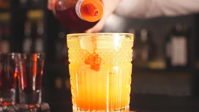 Bartender pours syrup in exotic fruit cocktail, Exotic fruit cocktail in glass isolated on blurred restaurant background
